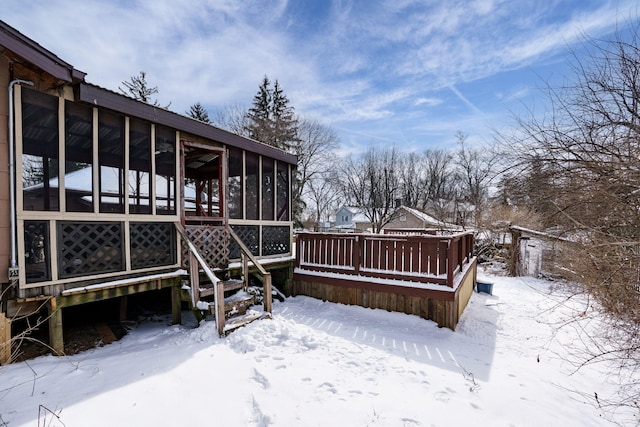 snowy yard featuring a deck and a sunroom