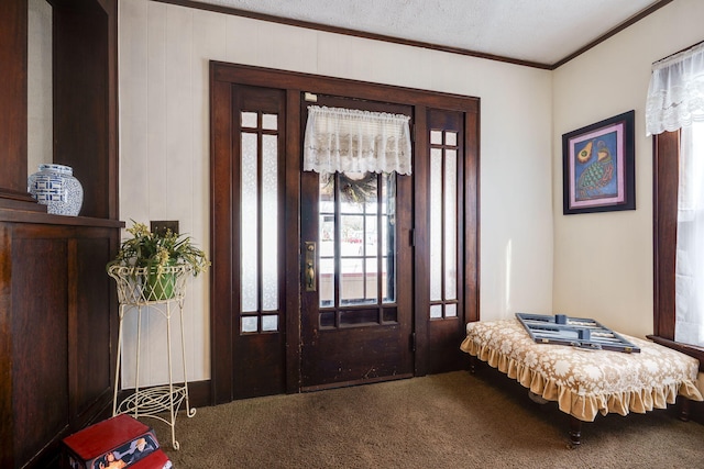 entryway with a textured ceiling, ornamental molding, and carpet flooring