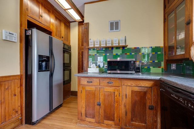 kitchen with light wood-type flooring, tasteful backsplash, and black appliances