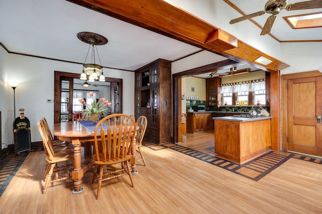 dining room with beamed ceiling, ceiling fan with notable chandelier, light hardwood / wood-style floors, bar area, and ornamental molding