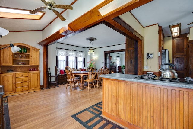 kitchen featuring ceiling fan, light hardwood / wood-style floors, hanging light fixtures, and crown molding