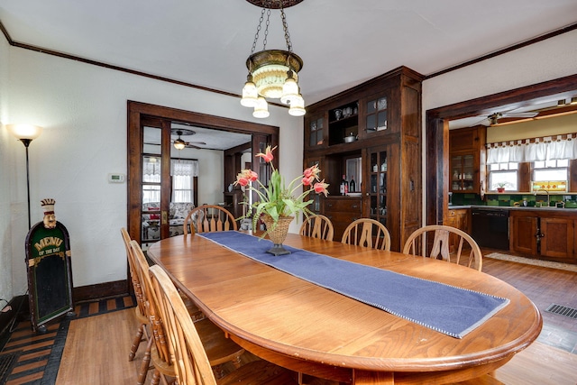 dining room featuring sink, crown molding, light hardwood / wood-style floors, and ceiling fan with notable chandelier