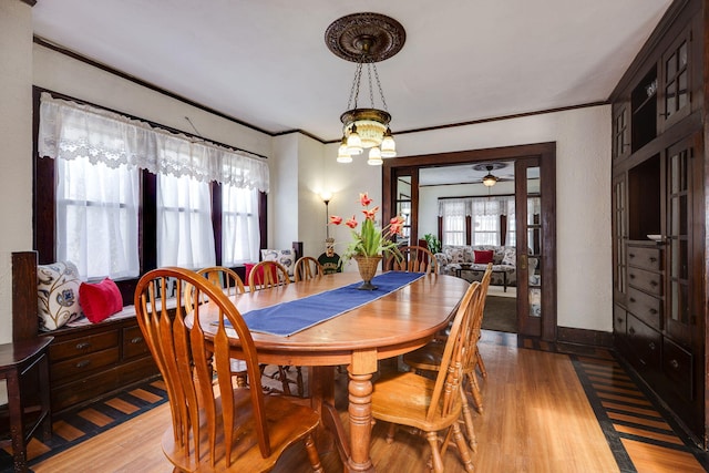 dining area with light wood-type flooring, crown molding, a chandelier, and a healthy amount of sunlight