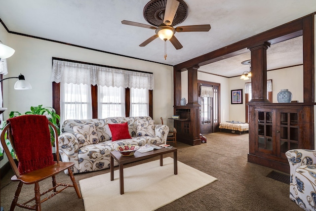 living room with ceiling fan with notable chandelier, carpet, crown molding, and decorative columns