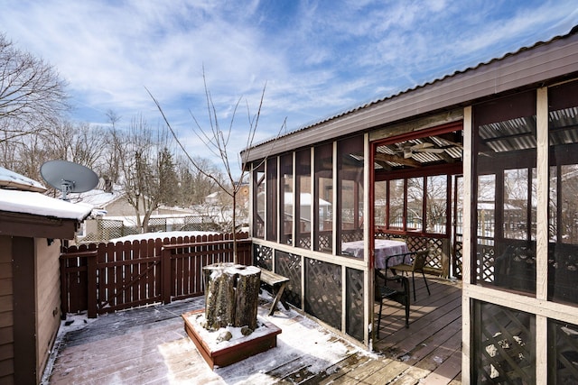 snow covered deck featuring a sunroom