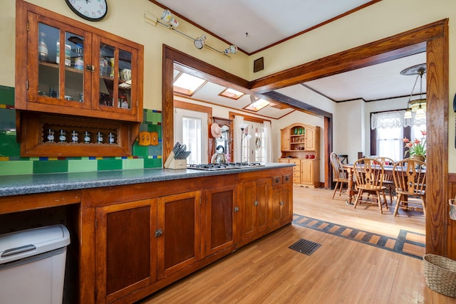 kitchen featuring light hardwood / wood-style floors, hanging light fixtures, crown molding, and stainless steel gas cooktop