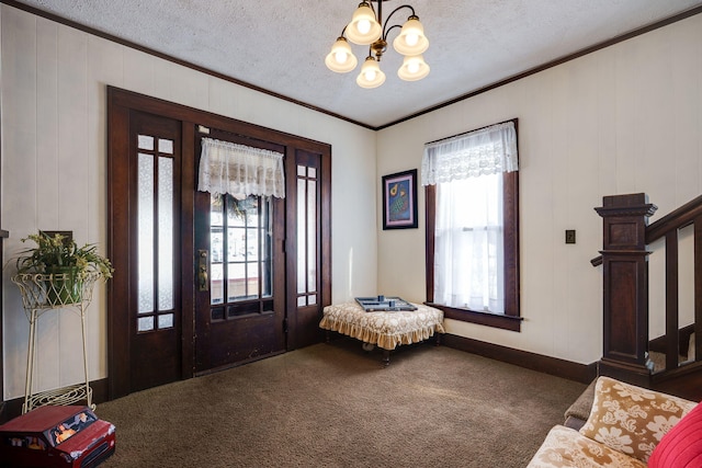 carpeted foyer featuring ornamental molding, an inviting chandelier, and a textured ceiling