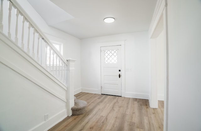 entrance foyer with light wood-style floors, baseboards, and stairs