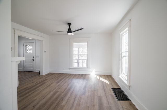 spare room with visible vents, ceiling fan, baseboards, and wood finished floors