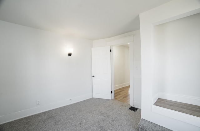 carpeted spare room featuring visible vents and baseboards