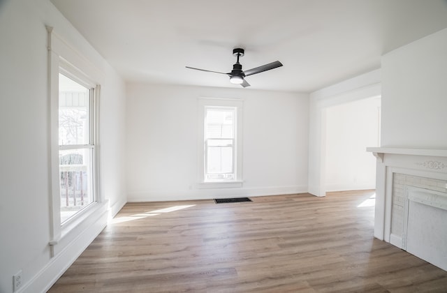 unfurnished living room with ceiling fan, light wood finished floors, visible vents, and baseboards