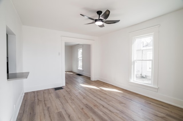 unfurnished room featuring visible vents, ceiling fan, baseboards, and wood finished floors