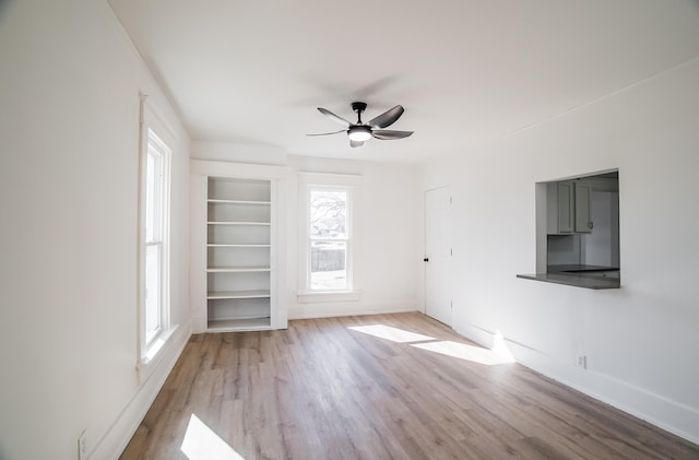 interior space featuring ceiling fan, wood finished floors, built in features, and baseboards