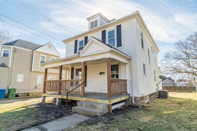 american foursquare style home with a porch, central AC unit, fence, and a front yard