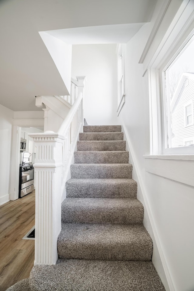 staircase with baseboards and wood finished floors