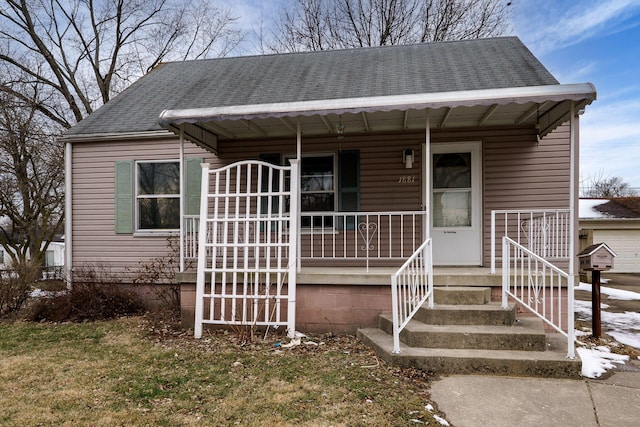 bungalow featuring a front lawn and roof with shingles