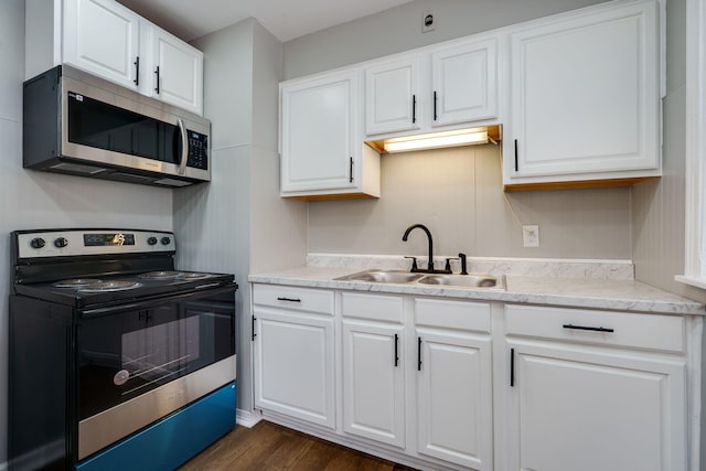 kitchen with stainless steel appliances, a sink, light countertops, and white cabinetry