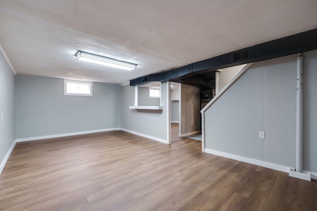 below grade area featuring light wood-type flooring, visible vents, stairs, and baseboards