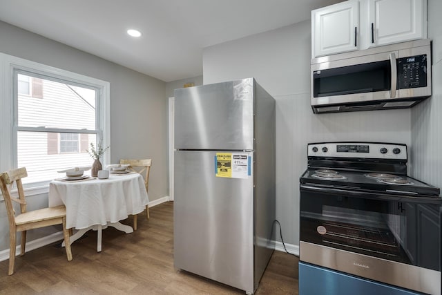 kitchen with recessed lighting, wood finished floors, white cabinetry, baseboards, and appliances with stainless steel finishes