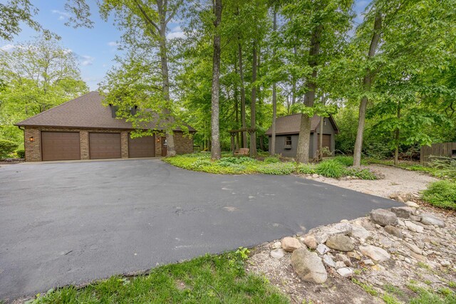 129 Tanglewood Dr, West Liberty, OH 43357 - view of front of property with brick siding, an outbuilding, driveway, and a shingled roof