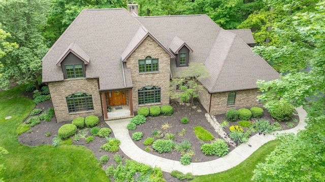 129 Tanglewood Dr, West Liberty, OH 43357 - view of front of home featuring brick siding, roof with shingles, a chimney, and a front lawn