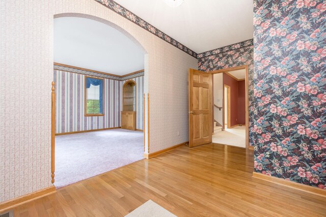 129 Tanglewood Dr, West Liberty, OH 43357 - unfurnished room with wood finished floors, wallpapered walls, arched walkways, and baseboards