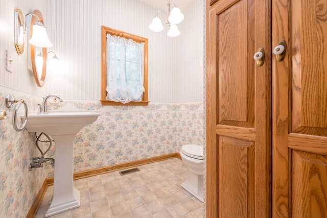 129 Tanglewood Dr, West Liberty, OH 43357 - bathroom featuring wallpapered walls, toilet, a chandelier, and baseboards