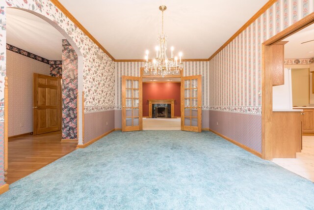 129 Tanglewood Dr, West Liberty, OH 43357 - unfurnished living room with wallpapered walls, french doors, arched walkways, carpet flooring, and crown molding