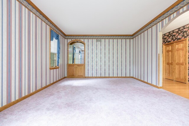 129 Tanglewood Dr, West Liberty, OH 43357 - spare room with wallpapered walls, light colored carpet, baseboards, arched walkways, and crown molding