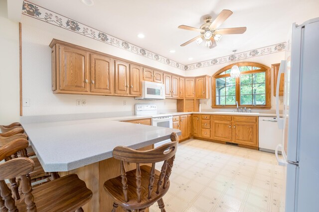 129 Tanglewood Dr, West Liberty, OH 43357 - kitchen with white appliances, a peninsula, a sink, a breakfast bar, and light flooring