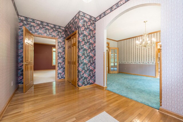 129 Tanglewood Dr, West Liberty, OH 43357 - empty room featuring light wood-type flooring, arched walkways, a chandelier, wallpapered walls, and baseboards