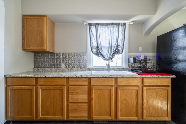 1920 Coventry Rd, Dayton, OH 45420 - kitchen featuring a sink, freestanding refrigerator, tasteful backsplash, and brown cabinetry