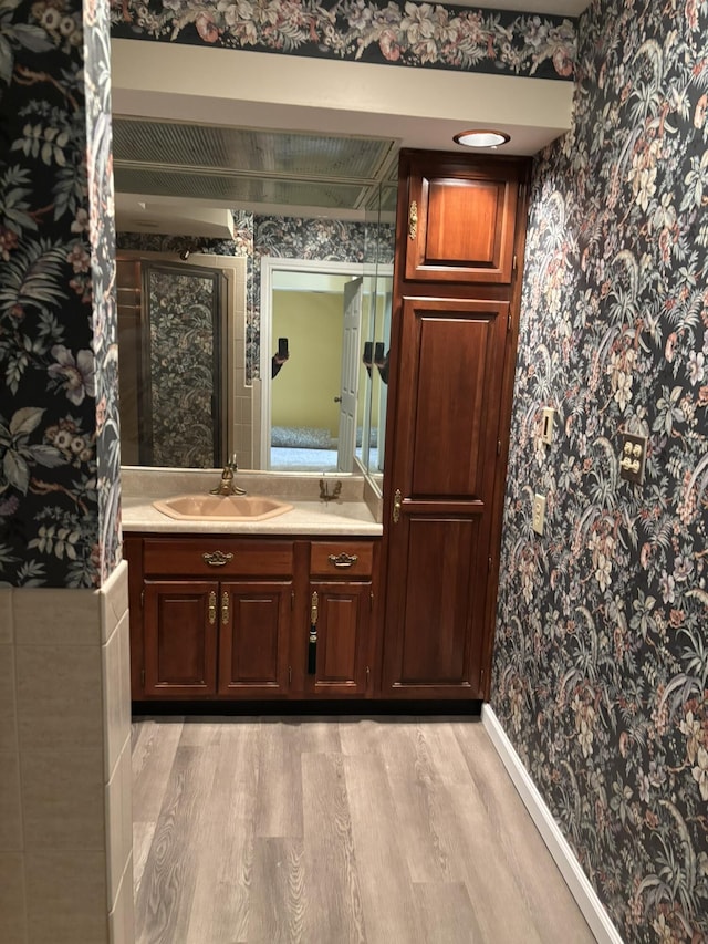 full bath featuring wood finished floors, vanity, and wallpapered walls