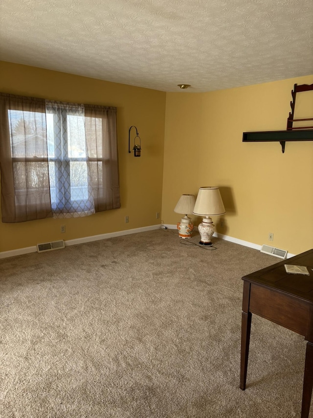 unfurnished room featuring carpet, visible vents, a textured ceiling, and baseboards