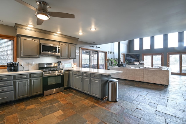 kitchen featuring gray cabinetry, a peninsula, light countertops, appliances with stainless steel finishes, and stone tile flooring