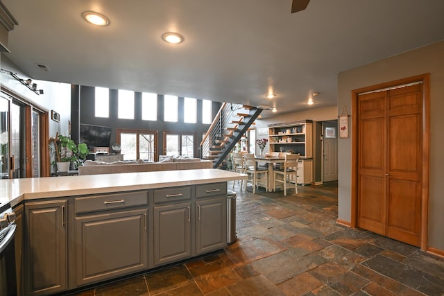 kitchen featuring stone tile floors, visible vents, open floor plan, light countertops, and gray cabinetry