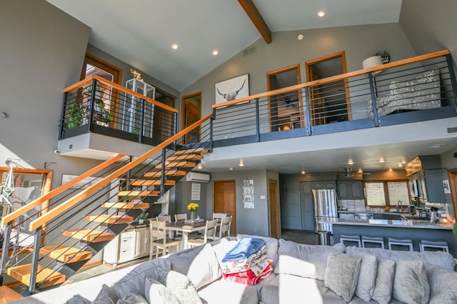 living area with beam ceiling, a wall unit AC, visible vents, stairway, and high vaulted ceiling