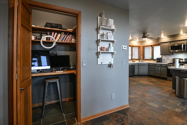 kitchen with stainless steel appliances, stone tile flooring, light countertops, gray cabinetry, and a ceiling fan