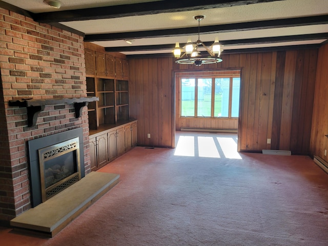unfurnished living room featuring beamed ceiling, a brick fireplace, wood walls, and a notable chandelier