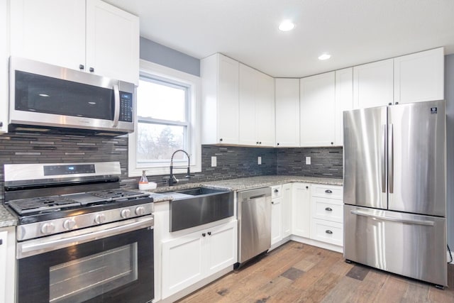 kitchen with white cabinetry, appliances with stainless steel finishes, and light stone counters