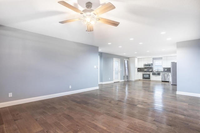 unfurnished living room with ceiling fan, dark hardwood / wood-style flooring, and sink