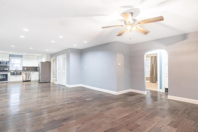 unfurnished living room featuring sink, dark hardwood / wood-style floors, and ceiling fan