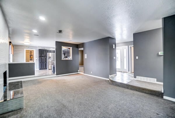 unfurnished living room with a textured ceiling and carpet flooring