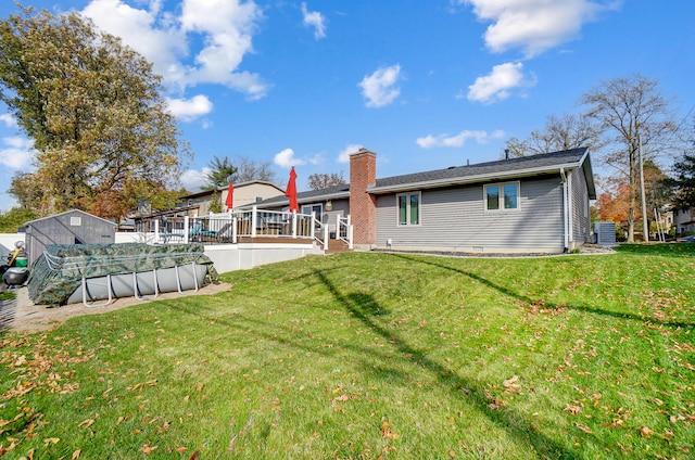 back of property featuring a pool side deck, a yard, and central AC