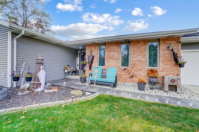 rear view of house featuring a garage, a yard, and a patio