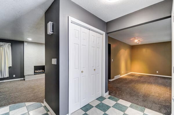 hallway featuring light carpet and a textured ceiling