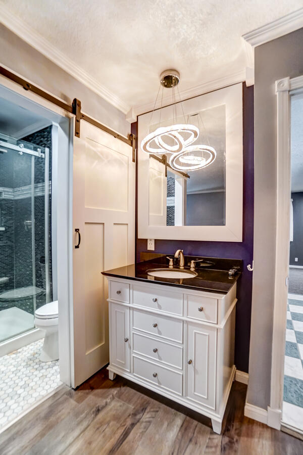 bathroom featuring ornamental molding, a shower with door, wood-type flooring, and vanity