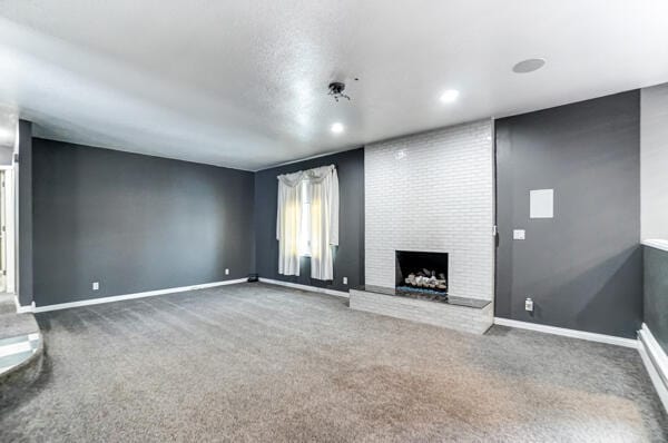 unfurnished living room featuring carpet floors and a brick fireplace