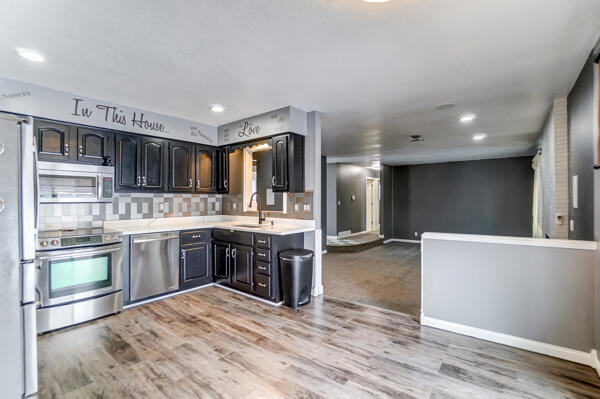 kitchen featuring stainless steel appliances, sink, backsplash, and light wood-type flooring