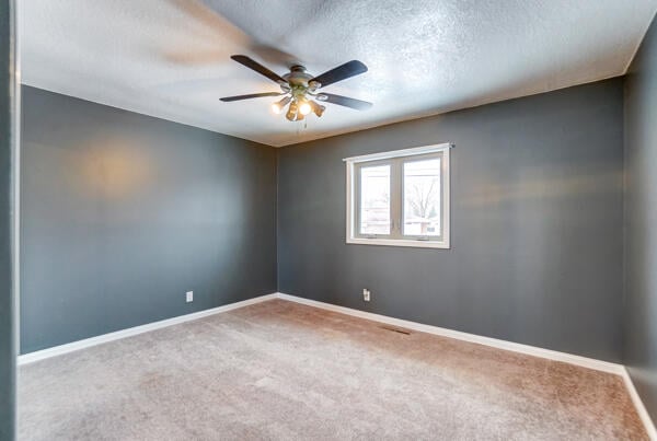 spare room featuring ceiling fan, carpet flooring, and a textured ceiling